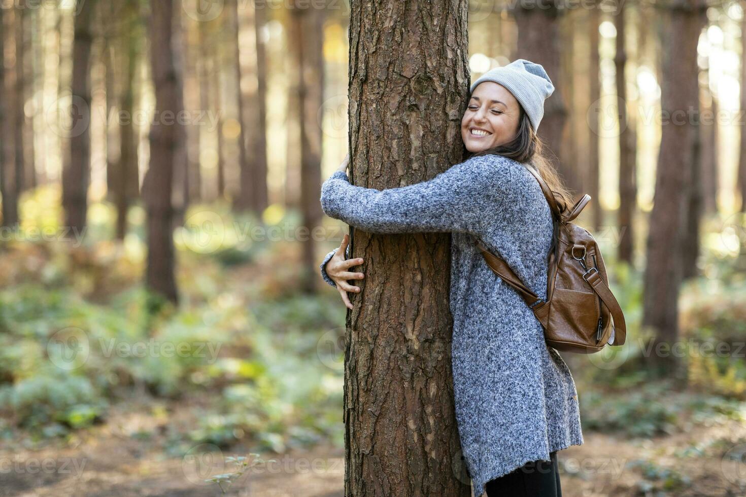 content femelle promeneur embrassement arbre tandis que randonnée dans cannock chasse des bois pendant hiver photo