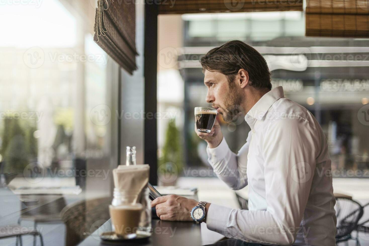 homme d'affaire avec tablette dans une café en buvant café de verre photo