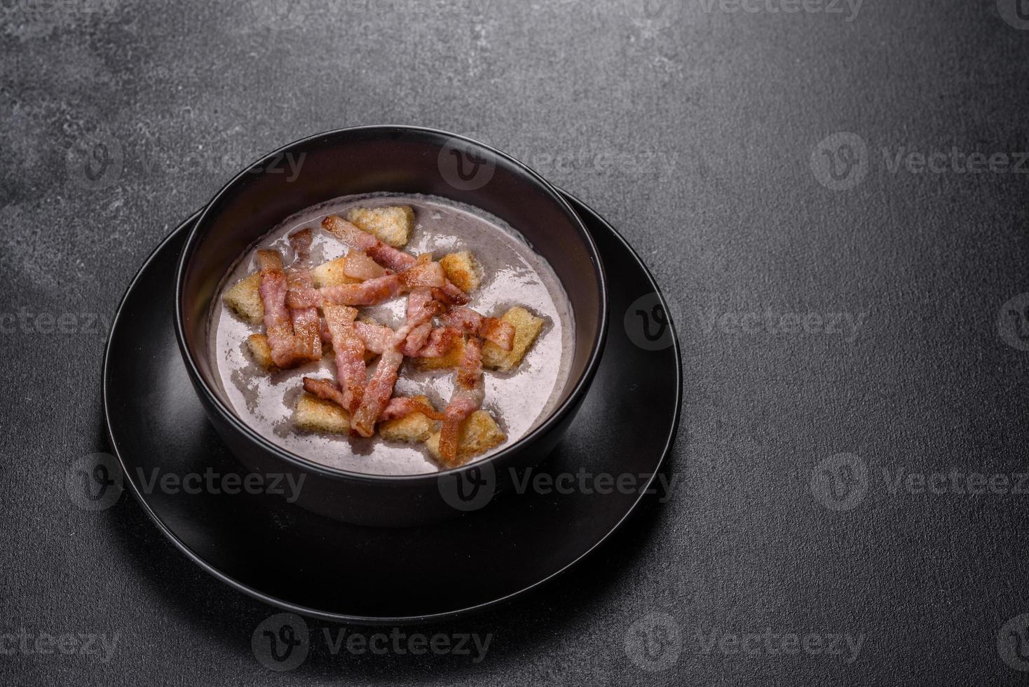 Soupe fraîche et délicieuse de purée chaude aux champignons et bacon dans une assiette noire photo