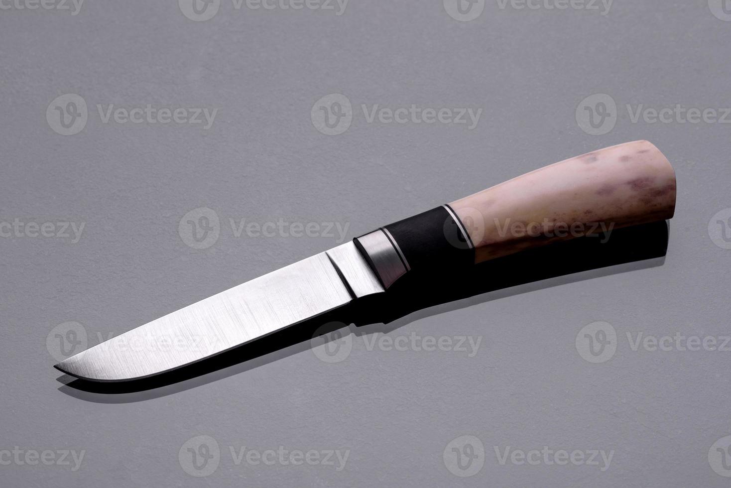 un grand couteau de chasse fait main allongé sur un fond sombre photo