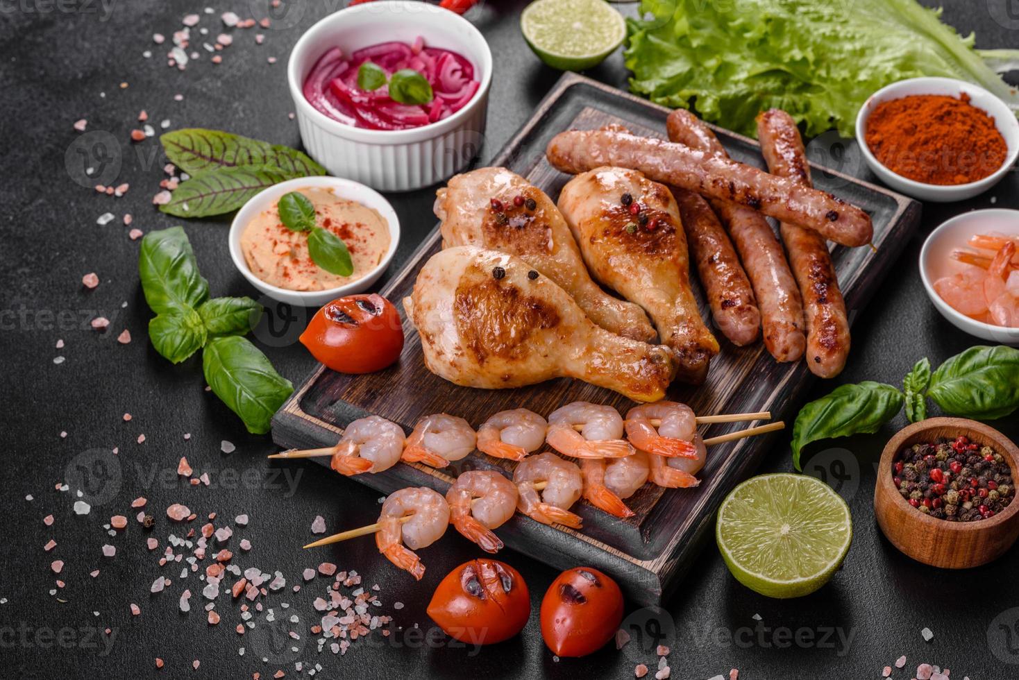 composition de saucisses, poulet, porc et crevettes préparés sur grill, ainsi que légumes préparés sur grill avec épices et herbes photo