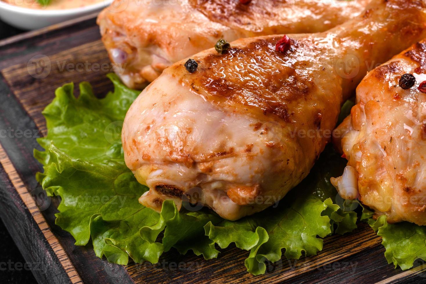 cuisses de poulet grillées savoureuses avec des épices et des herbes sur une planche de bois sur fond de béton foncé photo