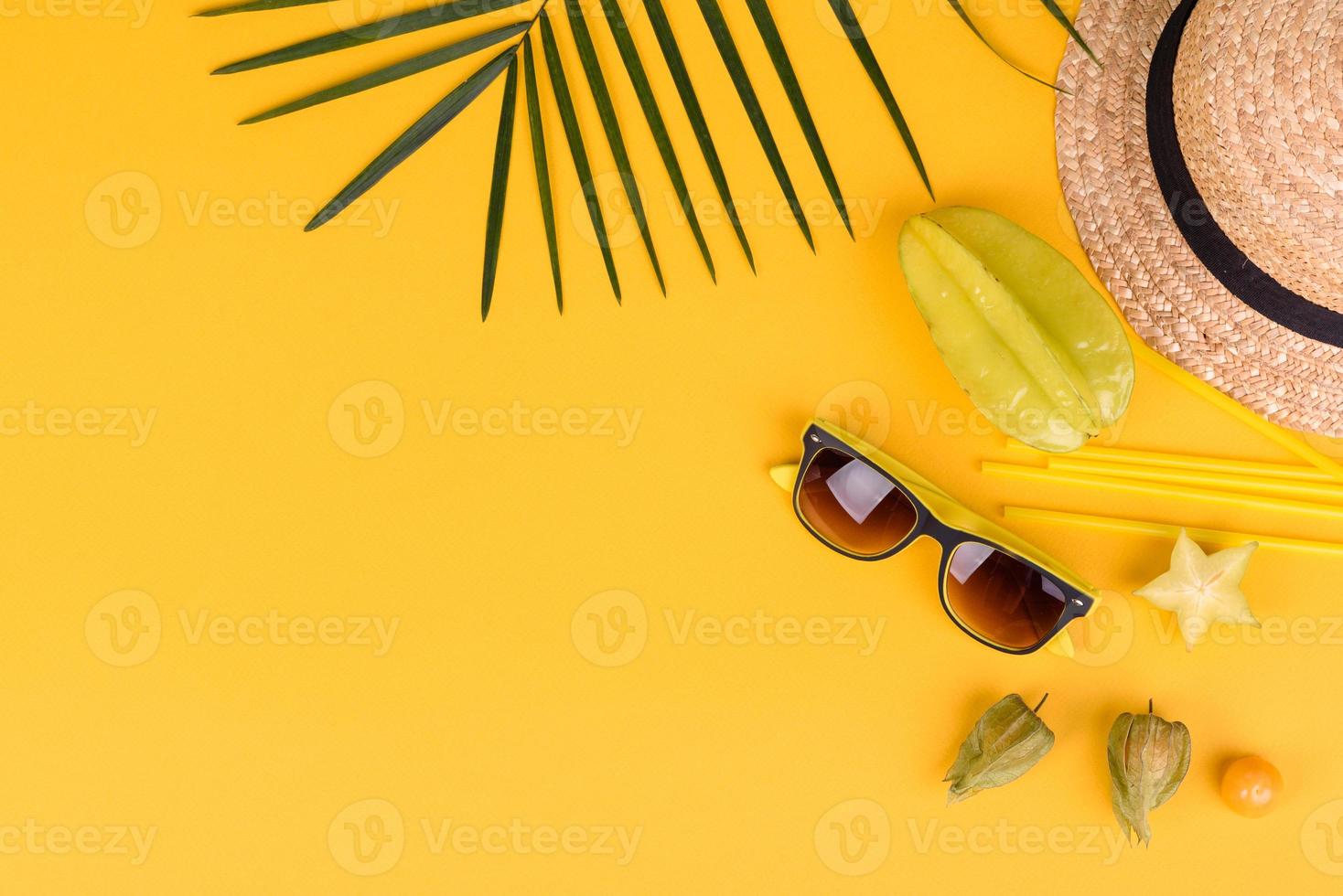 Carambole aux fruits, accessoires de plage et feuillage d'une plante tropicale sur papier de couleur photo