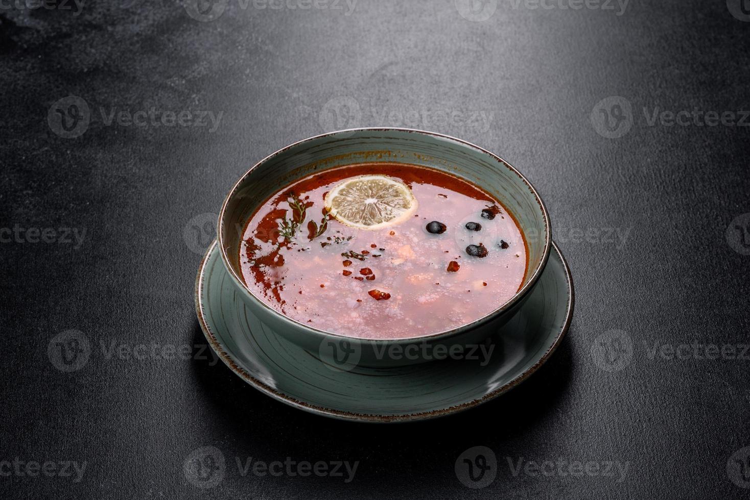 délicieuse soupe chaude fraîche à la tomate et à la viande dans une assiette en céramique. soupe méli-mélo photo