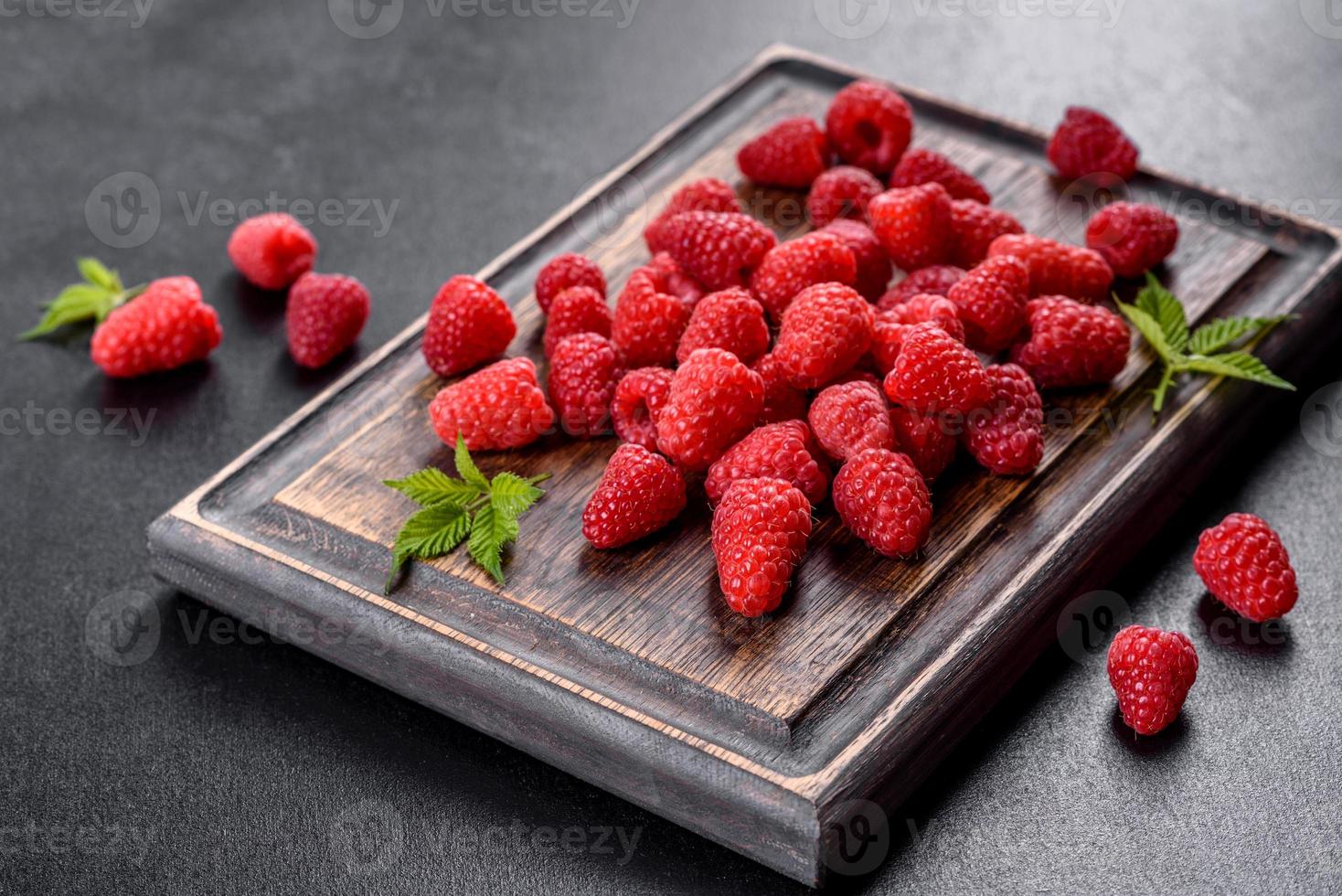 délicieuses framboises rouges juteuses fraîches sur une table sombre photo