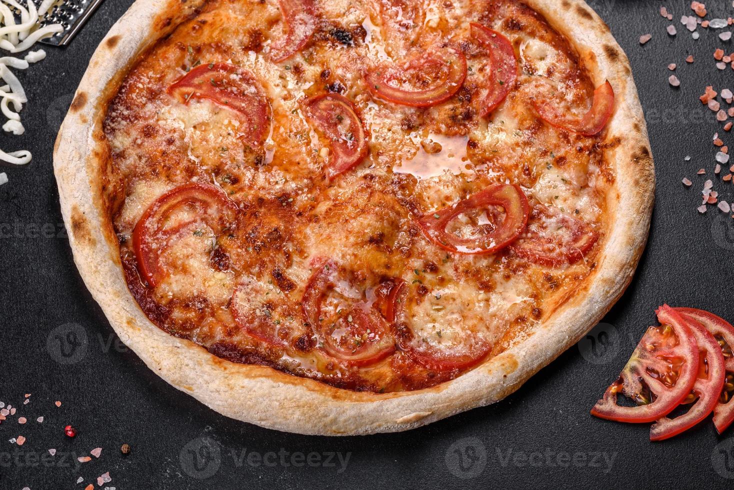 délicieuse pizza italienne fraîche aux champignons et tomates sur fond de béton foncé photo