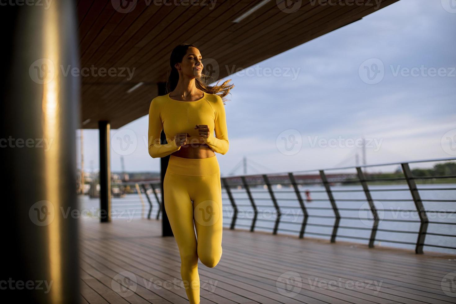 jeune femme prenant l'exercice de course par la promenade de la rivière photo
