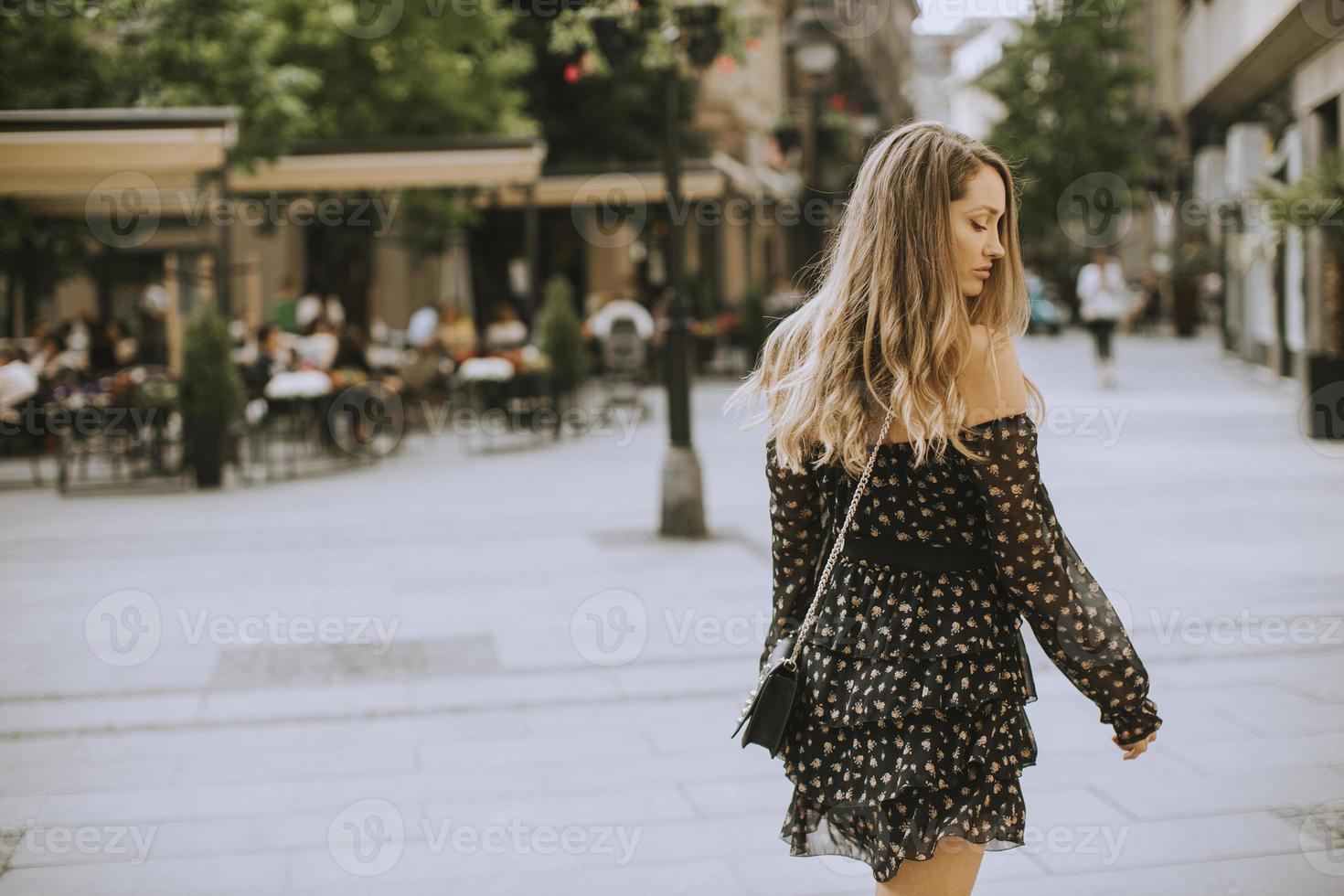 Jeune femme brune aux cheveux longs marchant dans la rue photo