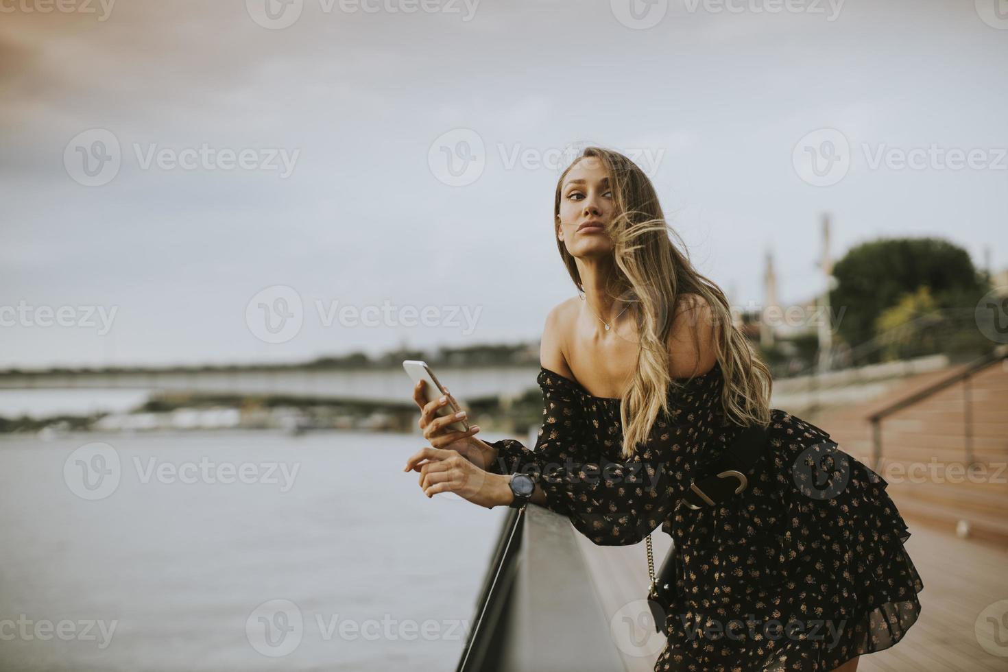 Jeune femme brune aux cheveux longs debout au bord de la rivière photo