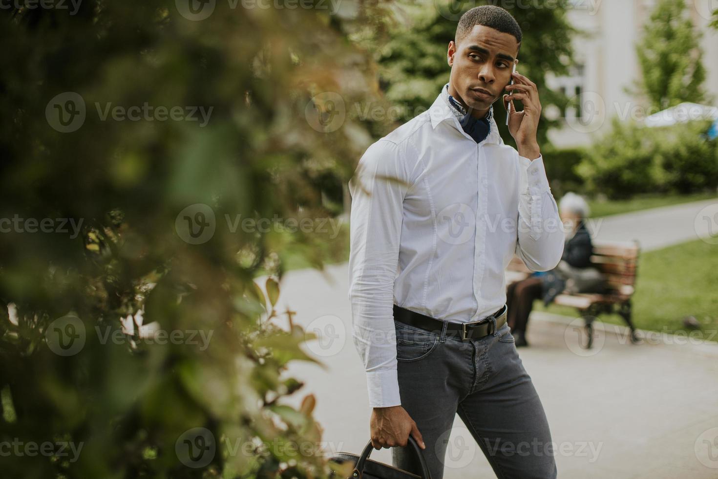 jeune homme d'affaires afro-américain à l'aide d'un téléphone mobile dans une rue photo