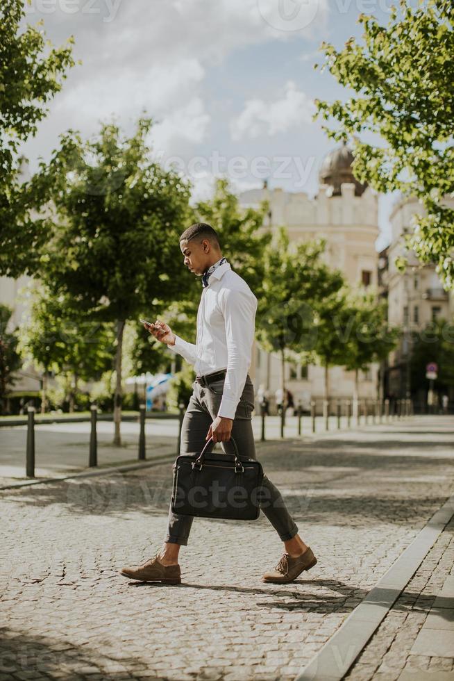 jeune homme d'affaires afro-américain à l'aide d'un téléphone mobile dans une rue photo