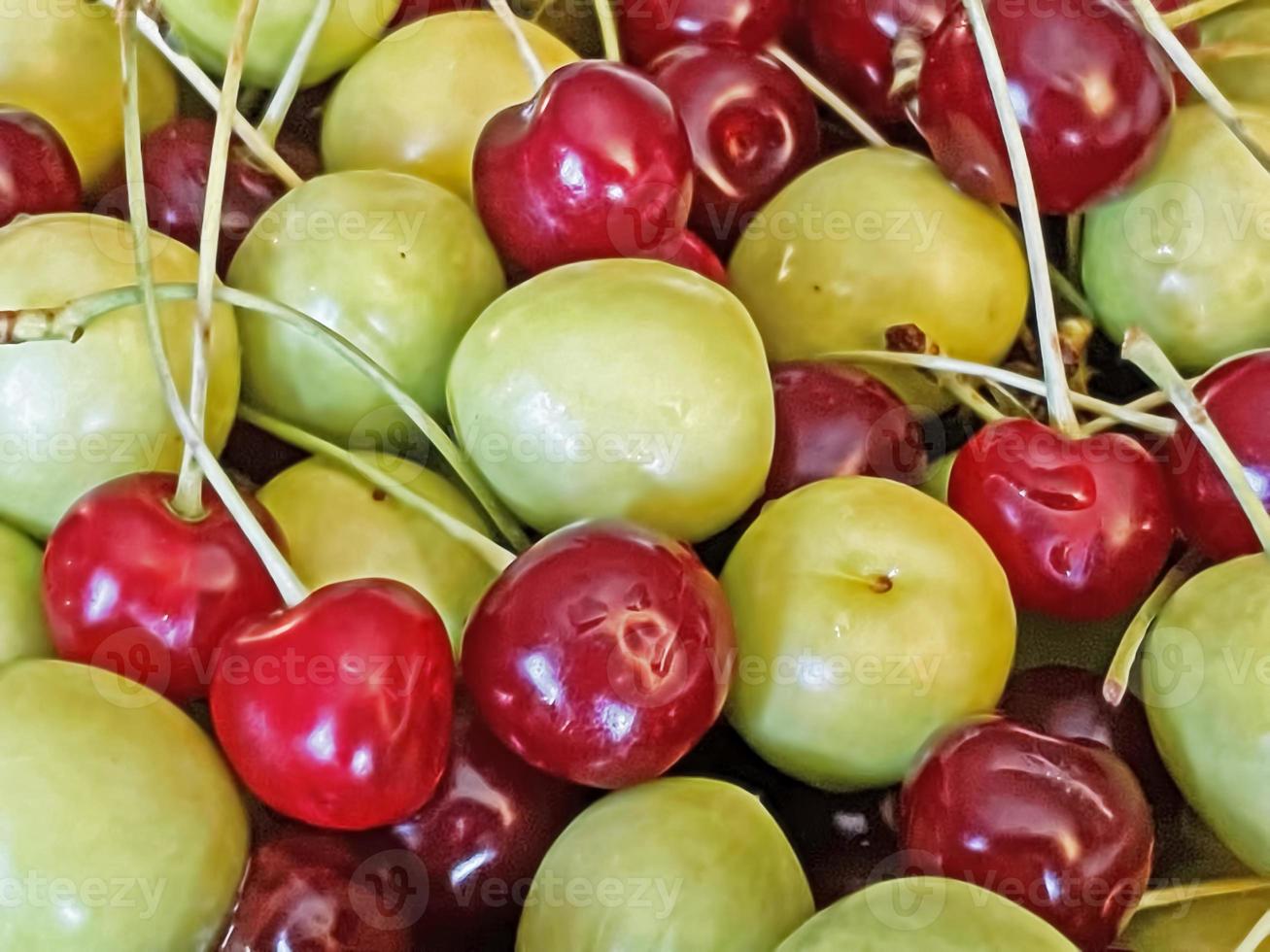 cerises aigres et prunes prêtes à manger et lavées sur une assiette verte photo