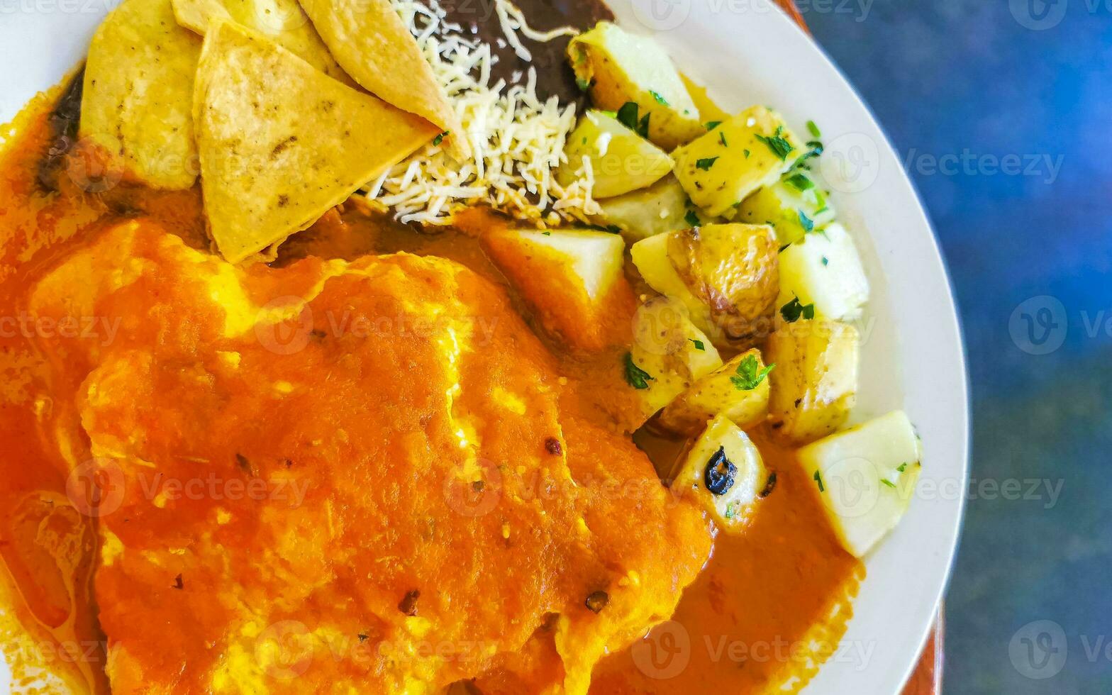 Oeufs d'omelette mexicaine haricots noirs pommes de terre nachos sur plaque blanche. photo