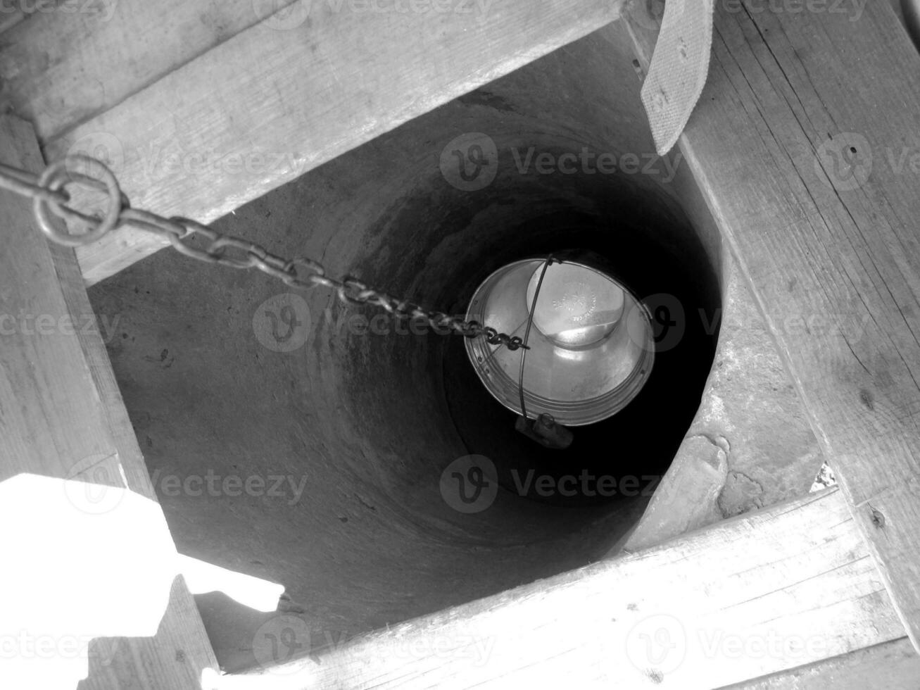 Vieux puits avec seau en fer sur longue chaîne forgée pour l'eau potable photo