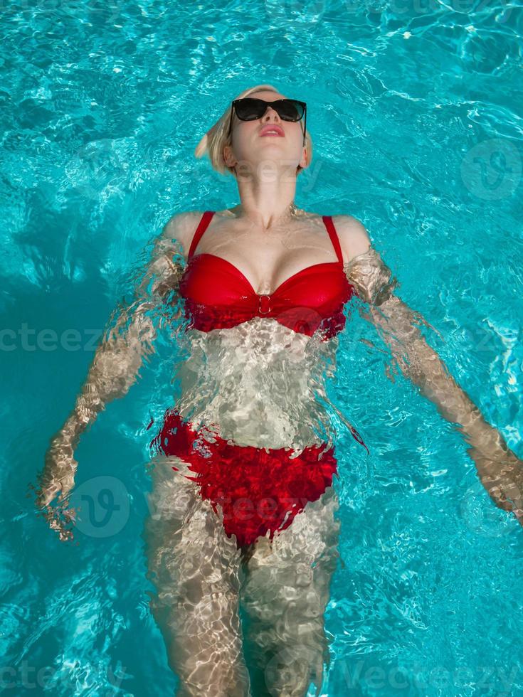 jeune belle fille sexy appréciant nager dans la piscine privée et se détendre au soleil photo