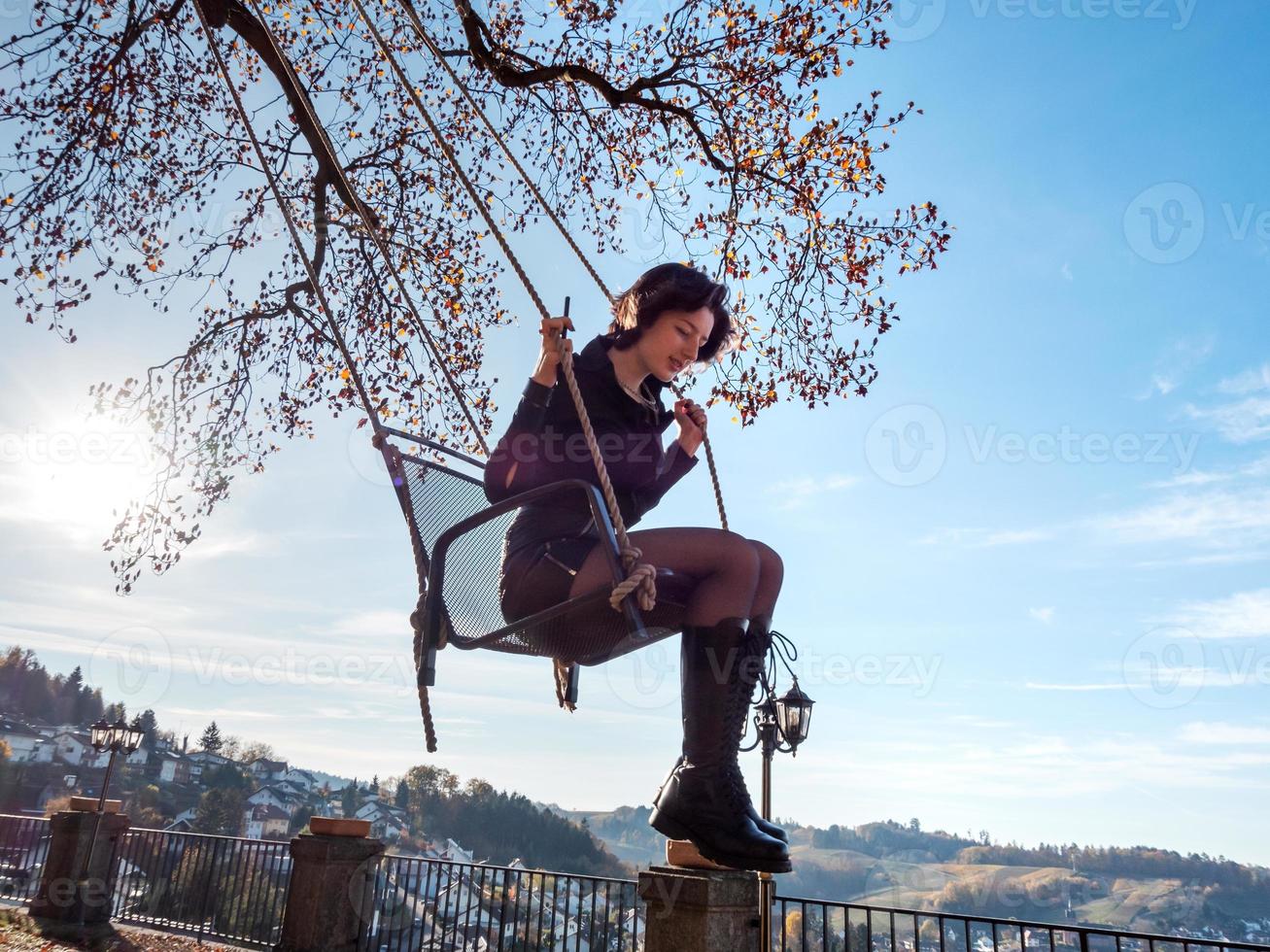 une jeune fille se balance sur une balançoire. journée ensoleillée. photo