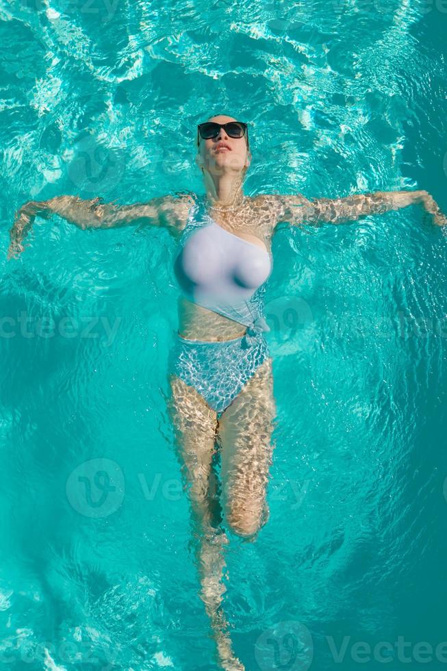 jeune belle fille sexy appréciant nager dans la piscine privée et se détendre au soleil photo