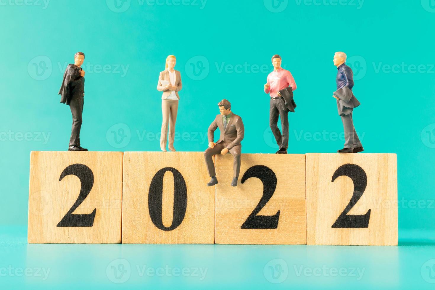 Les gens d'affaires miniatures debout sur un bloc de bois numéro 2022 photo