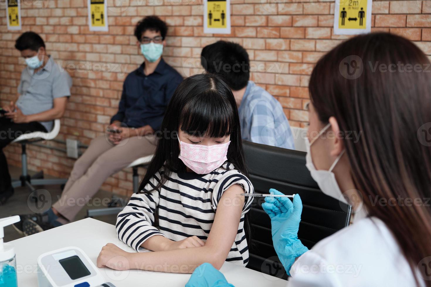 le médecin injecte une fille patiente avec des gens qui font la queue. photo