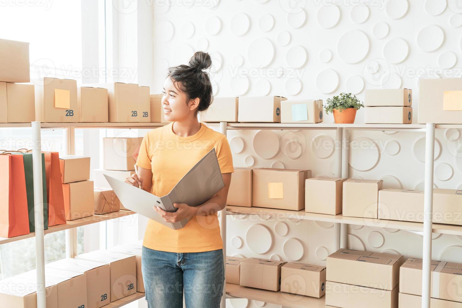 jeune femme asiatique vérifiant les marchandises sur l'étagère du stock à l'entrepôt - concept de vente ou d'achat en ligne photo