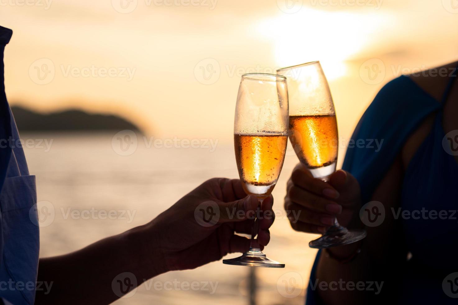 main tenant un verre à boire du vin sur fond de mer coucher de soleil. photo