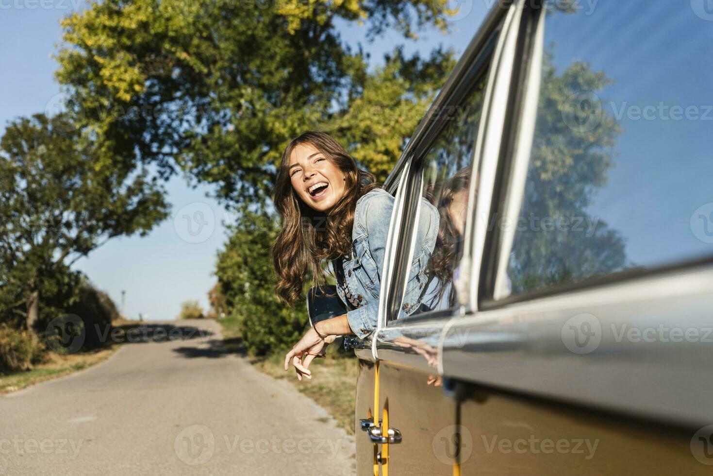jolie femme sur une route voyage avec sa campeur, à la recherche en dehors de voiture fenêtre photo