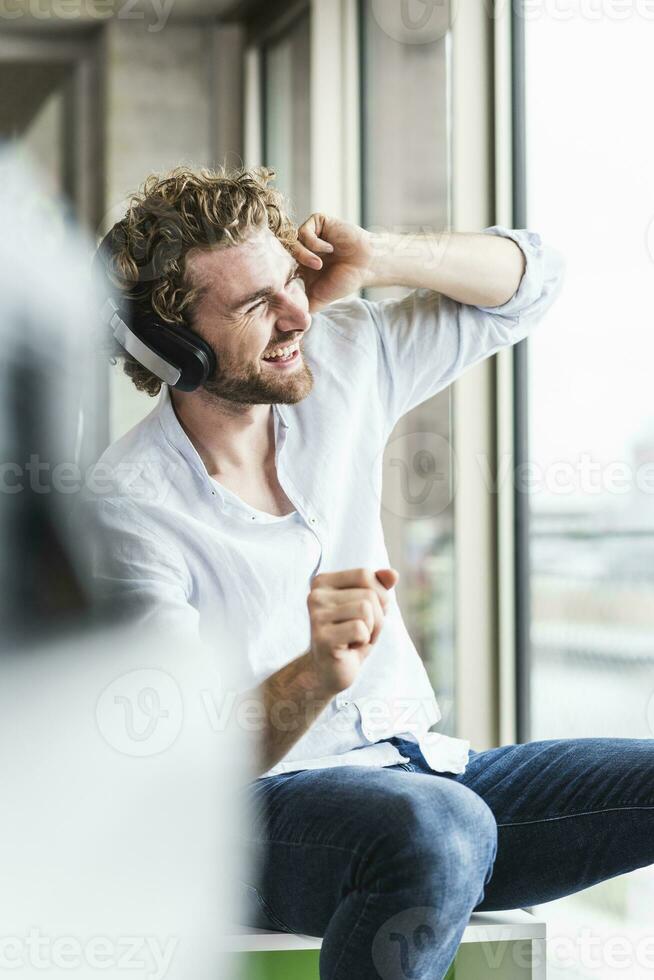 content décontractée Jeune homme écoute à la musique avec écouteurs à le fenêtre photo