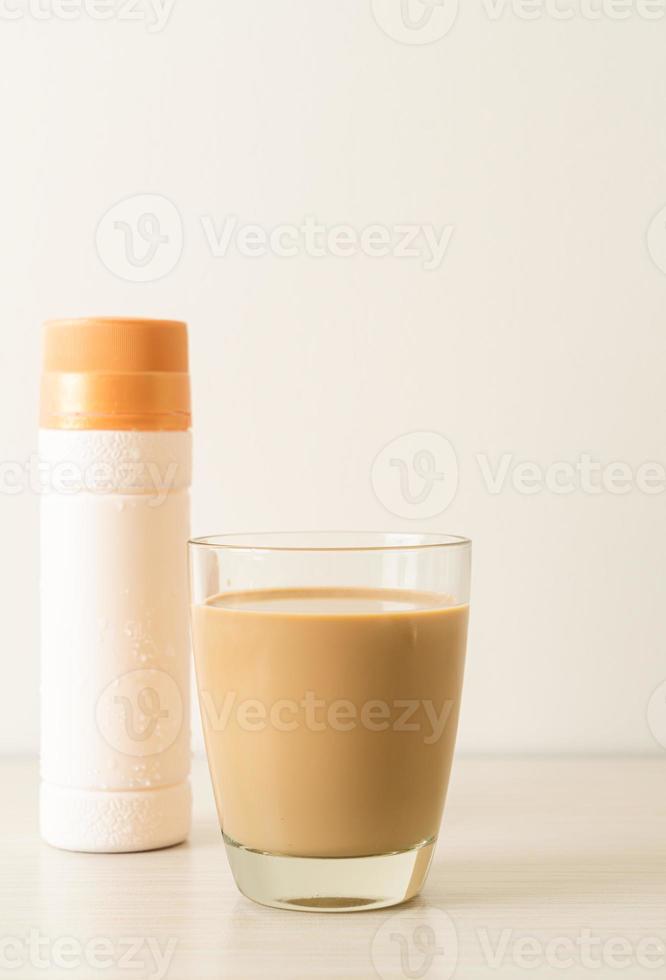 verre à café au lait avec des bouteilles de café prêtes à boire sur la table photo