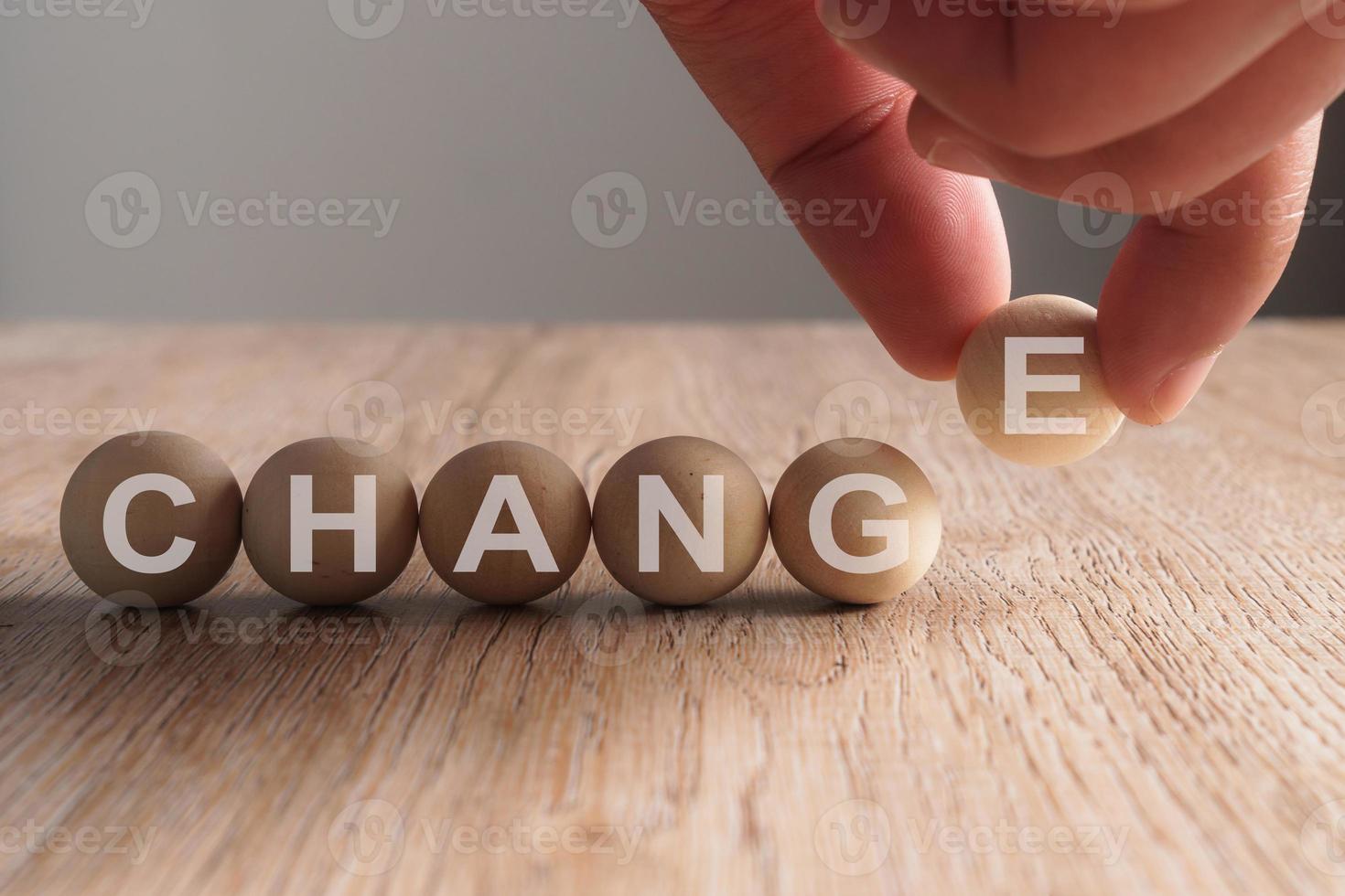 Mettre la main sur le mot de changement écrit en boule en bois photo