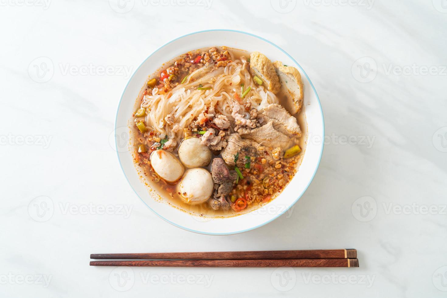 nouilles au porc et boulettes de viande dans une soupe épicée ou nouilles tom yum à l'asiatique photo