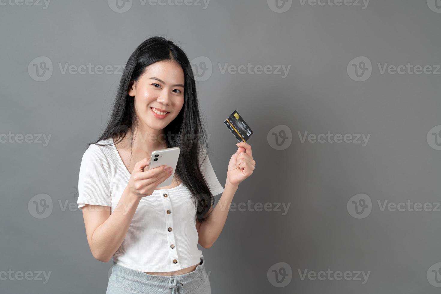 jeune femme asiatique utilisant un téléphone avec une main tenant une carte de crédit - concept de magasinage en ligne photo