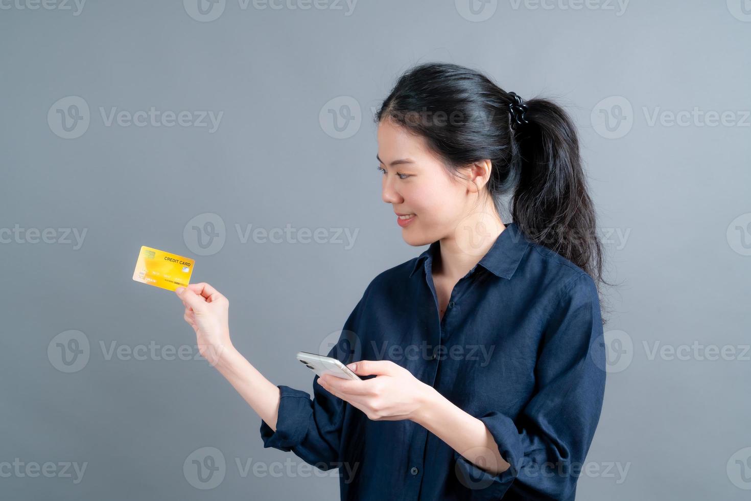 jeune fille asiatique montrant une carte de crédit en plastique tout en tenant un téléphone portable photo