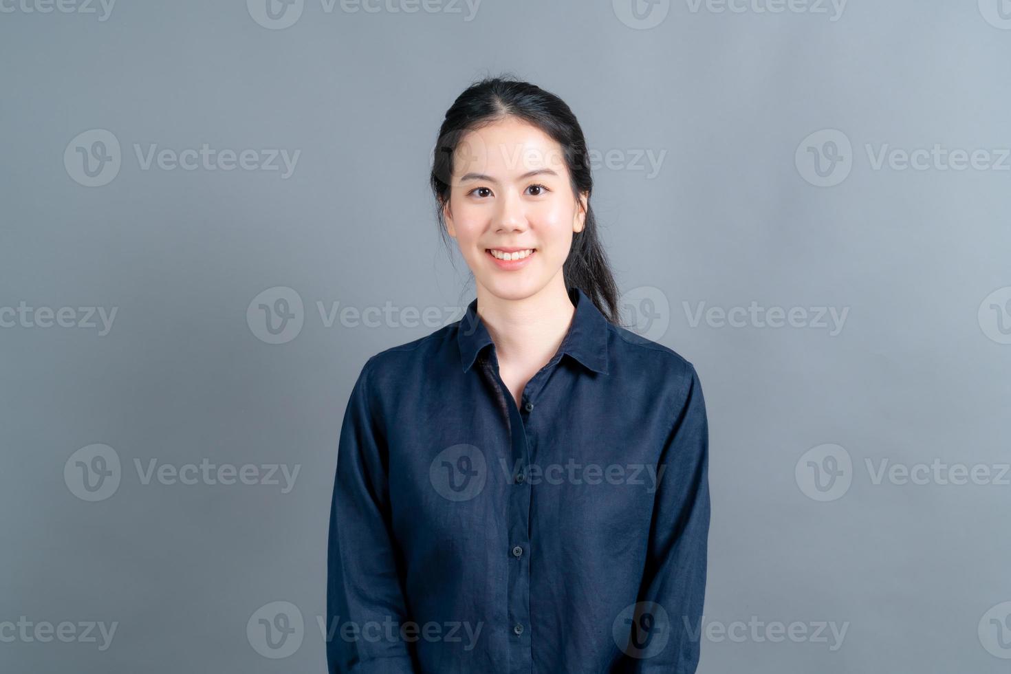 femme asiatique heureuse avec un visage heureux en chemise marine sur fond gris photo