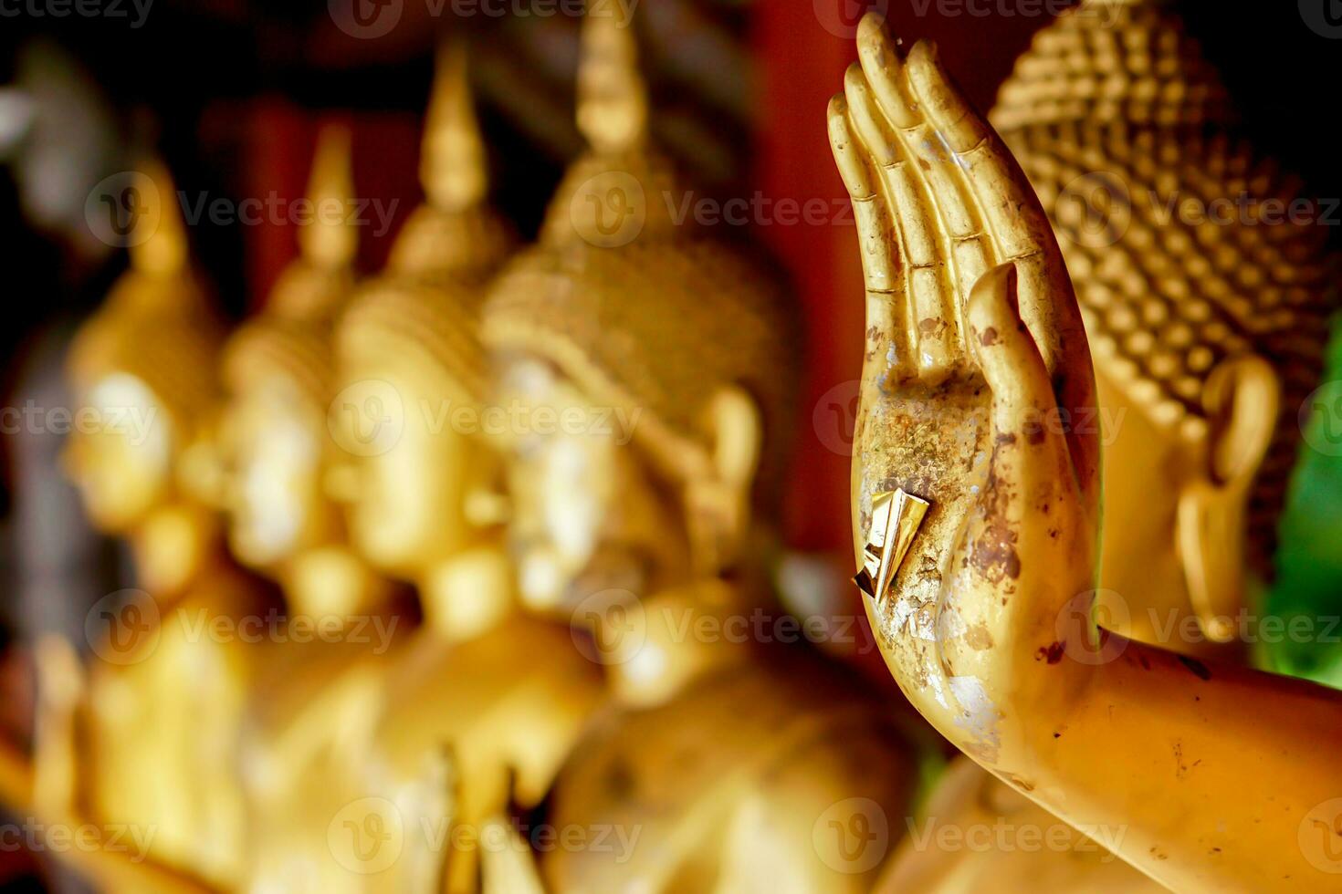gros plan et recadrer la main de la statue de bouddha doré avec une feuille d'or sur la statue de bouddha doré floue se tenir sur fond de ligne solide photo