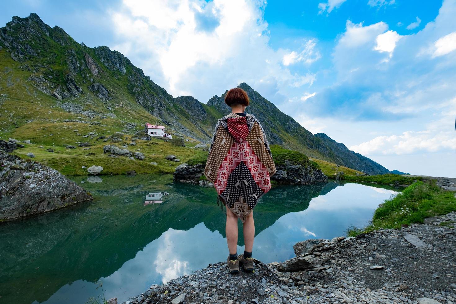 femme voyageur en poncho posant dans les montagnes photo