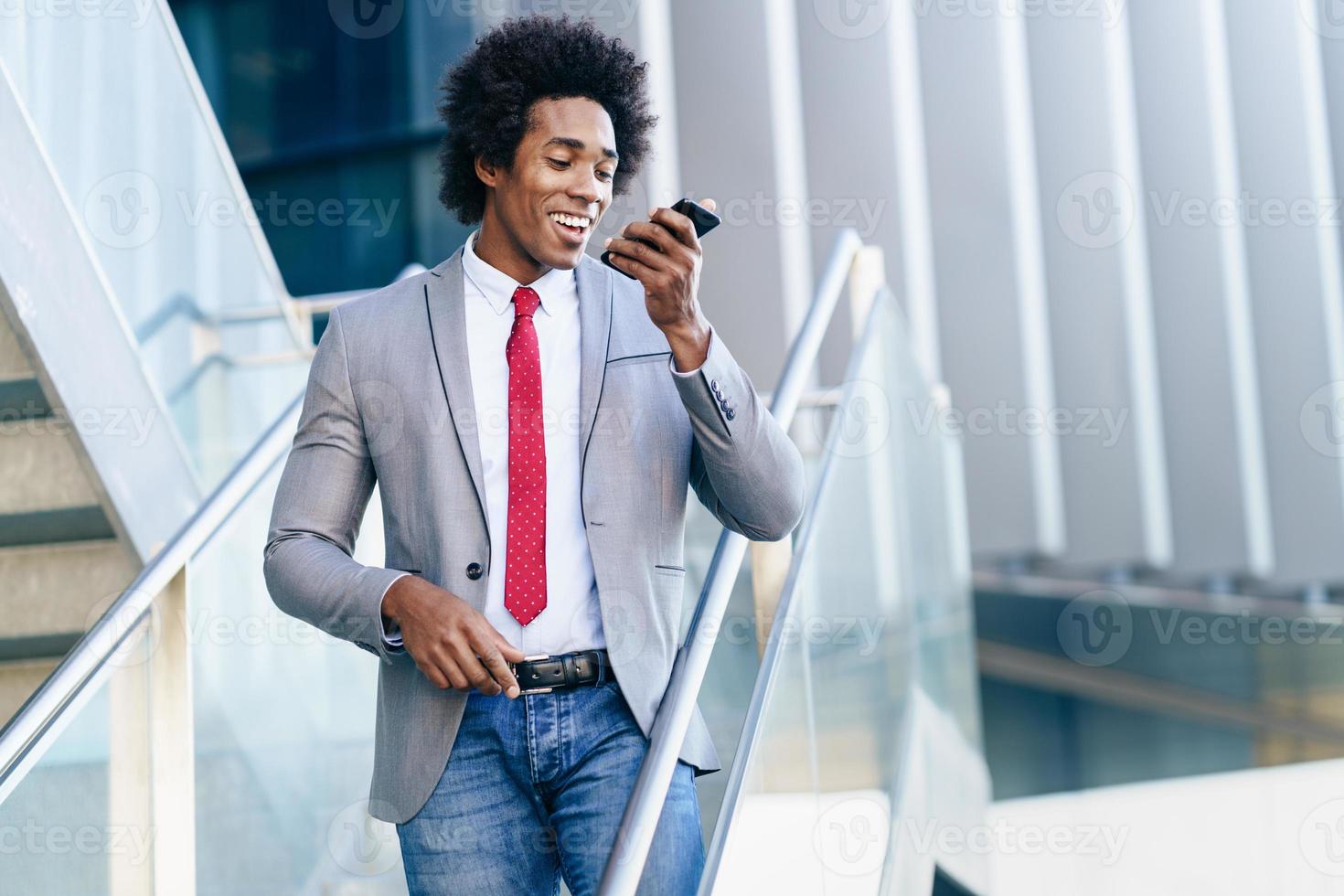 homme d'affaires noir utilisant un smartphone près d'un immeuble de bureaux photo