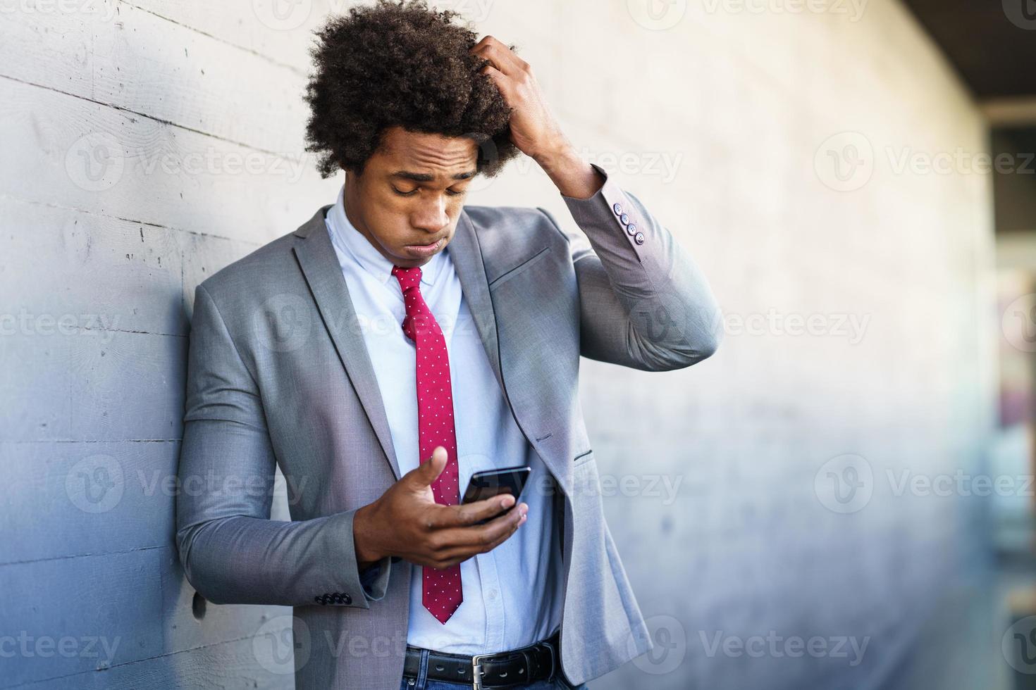 homme d'affaires noir inquiet utilisant son smartphone à l'extérieur. photo