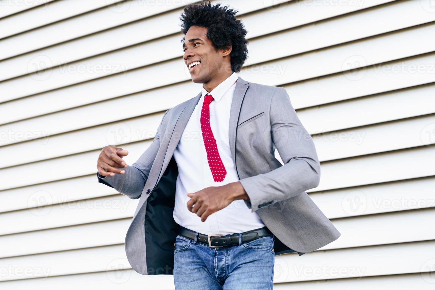 heureux homme d'affaires noir portant un costume dansant à l'extérieur. photo