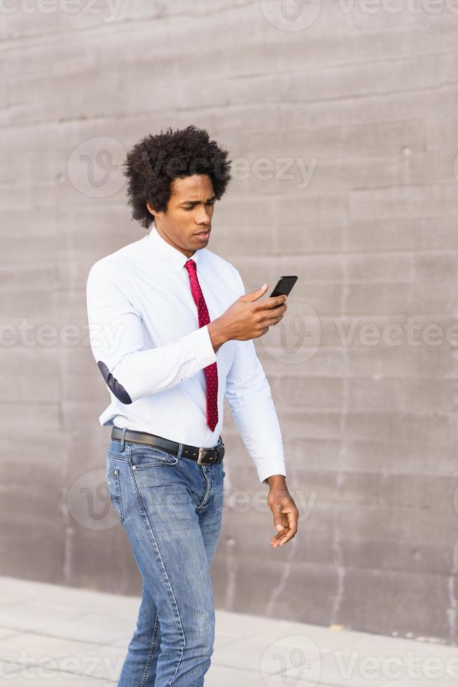 homme d'affaires noir utilisant un smartphone près d'un immeuble de bureaux photo