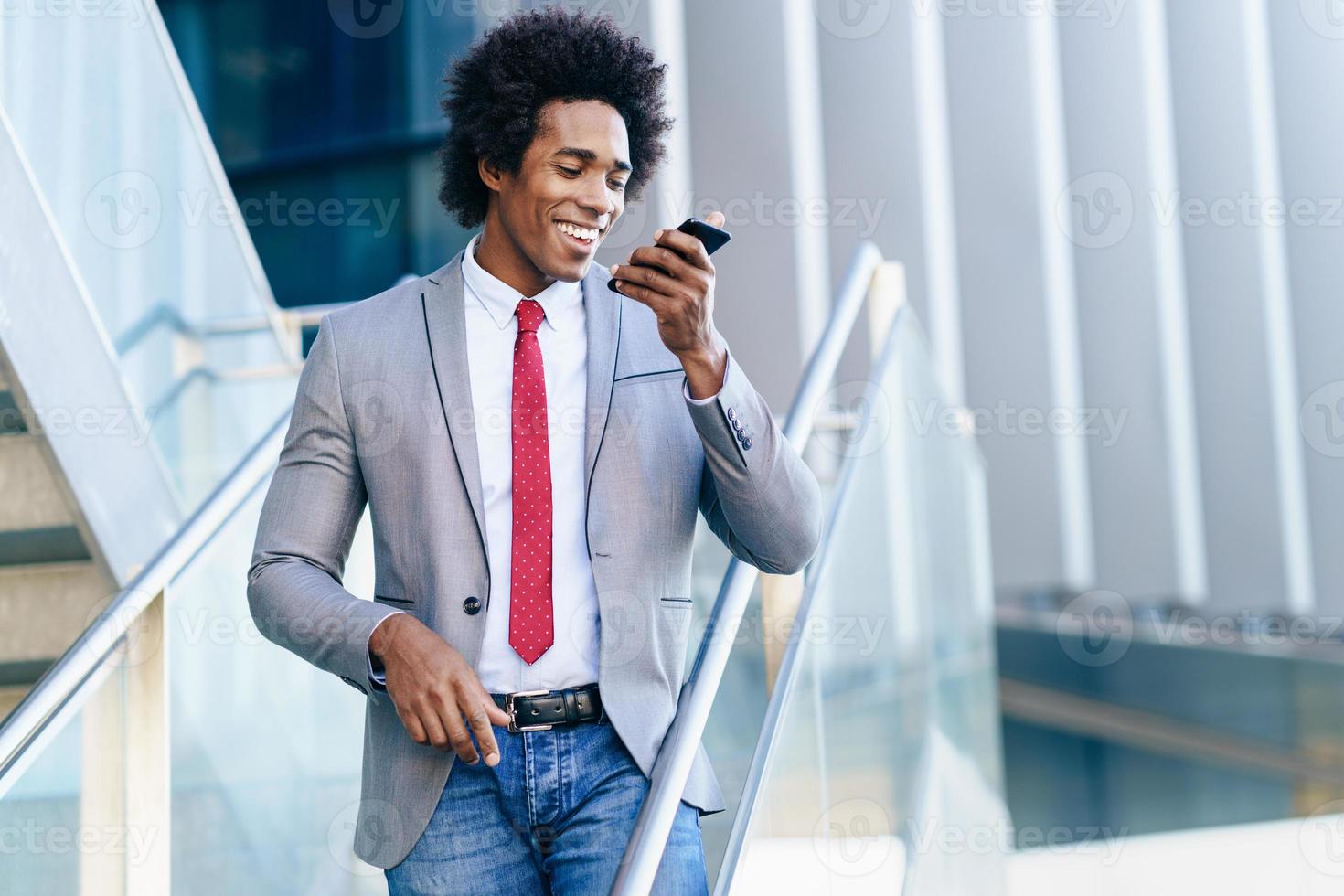 homme d'affaires noir utilisant un smartphone près d'un immeuble de bureaux photo