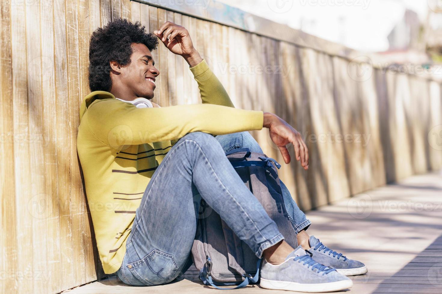 homme noir aux cheveux afro et casque reposant sur le sol. photo