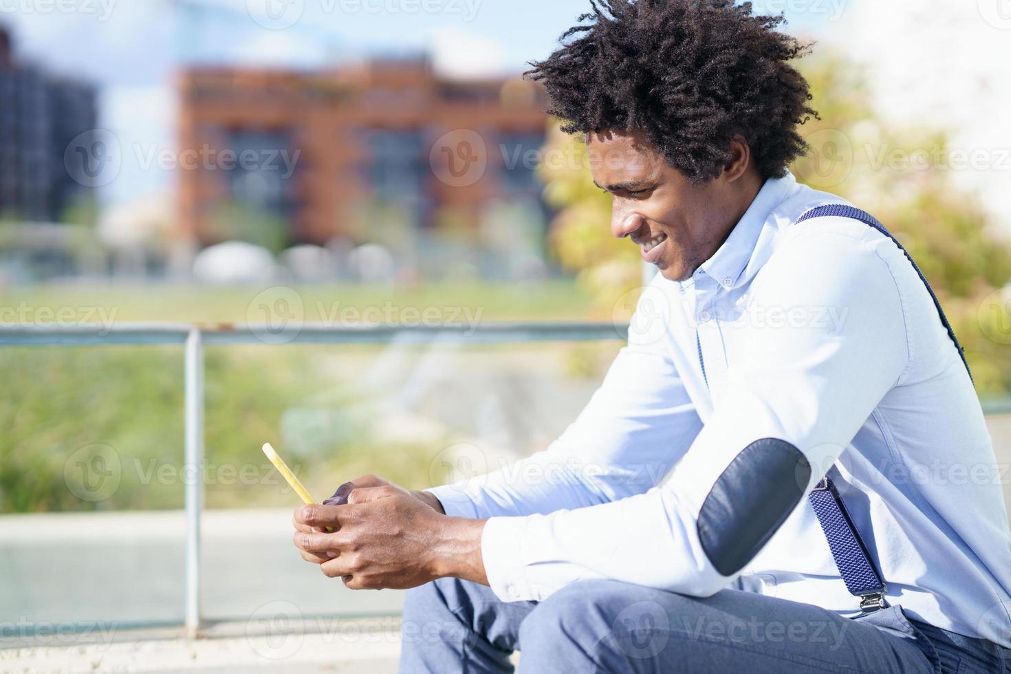 homme noir avec une coiffure afro à l'aide d'un smartphone photo