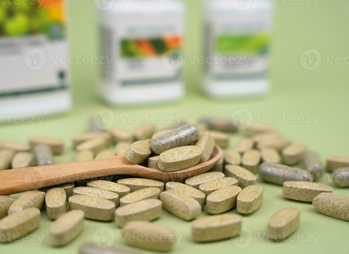 Naturel vitamines et suppléments dans une en bois cuillère sur une vert Contexte. en bonne santé mode de vie concept. fermer. sélectif se concentrer. photo