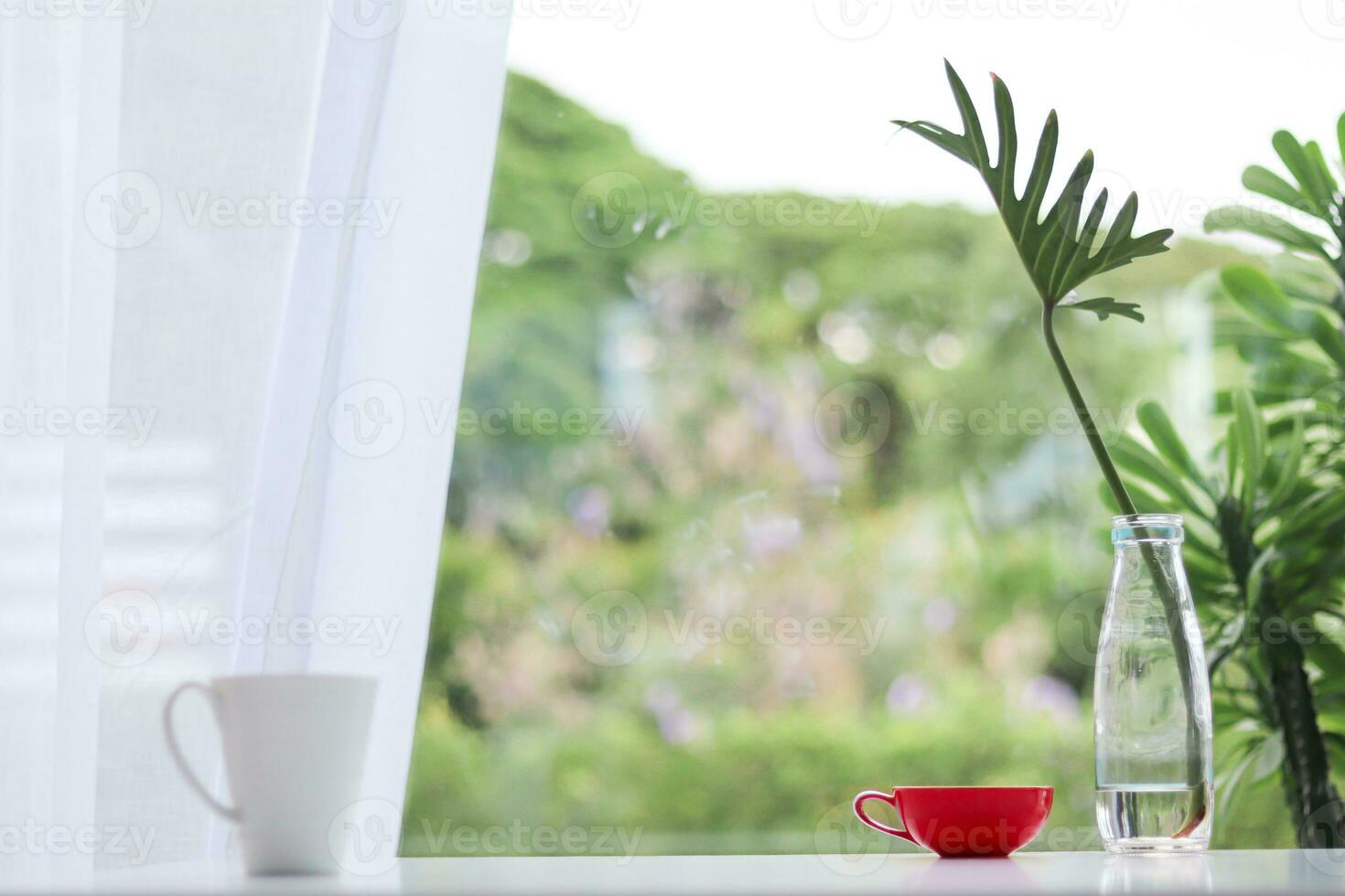 tasse de café est préparé sur table suivant à verre vase avec feuilles inséré à décorer table dans magnifique moderne style. tasse de chaud café sur table par fenêtre dans Matin et copie espace pour texte. photo