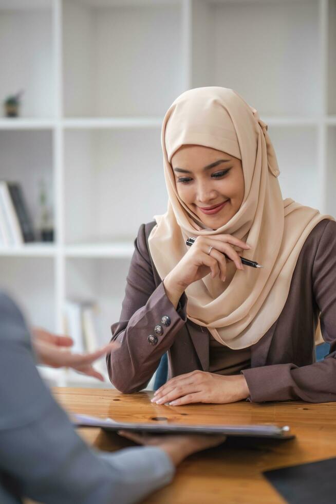 une professionnel et sur de soi asiatique musulman femme d'affaires discuter travail avec sa collègue dans le bureau. photo