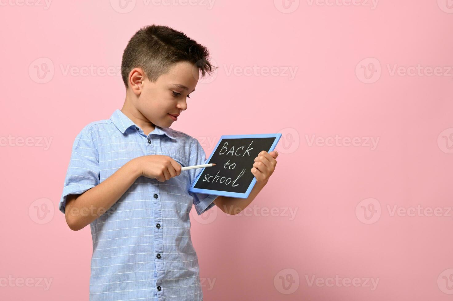 caractères retour à école sur une craie planche dans le mains de une content élève. isolé plus de rose Contexte avec copie espace photo