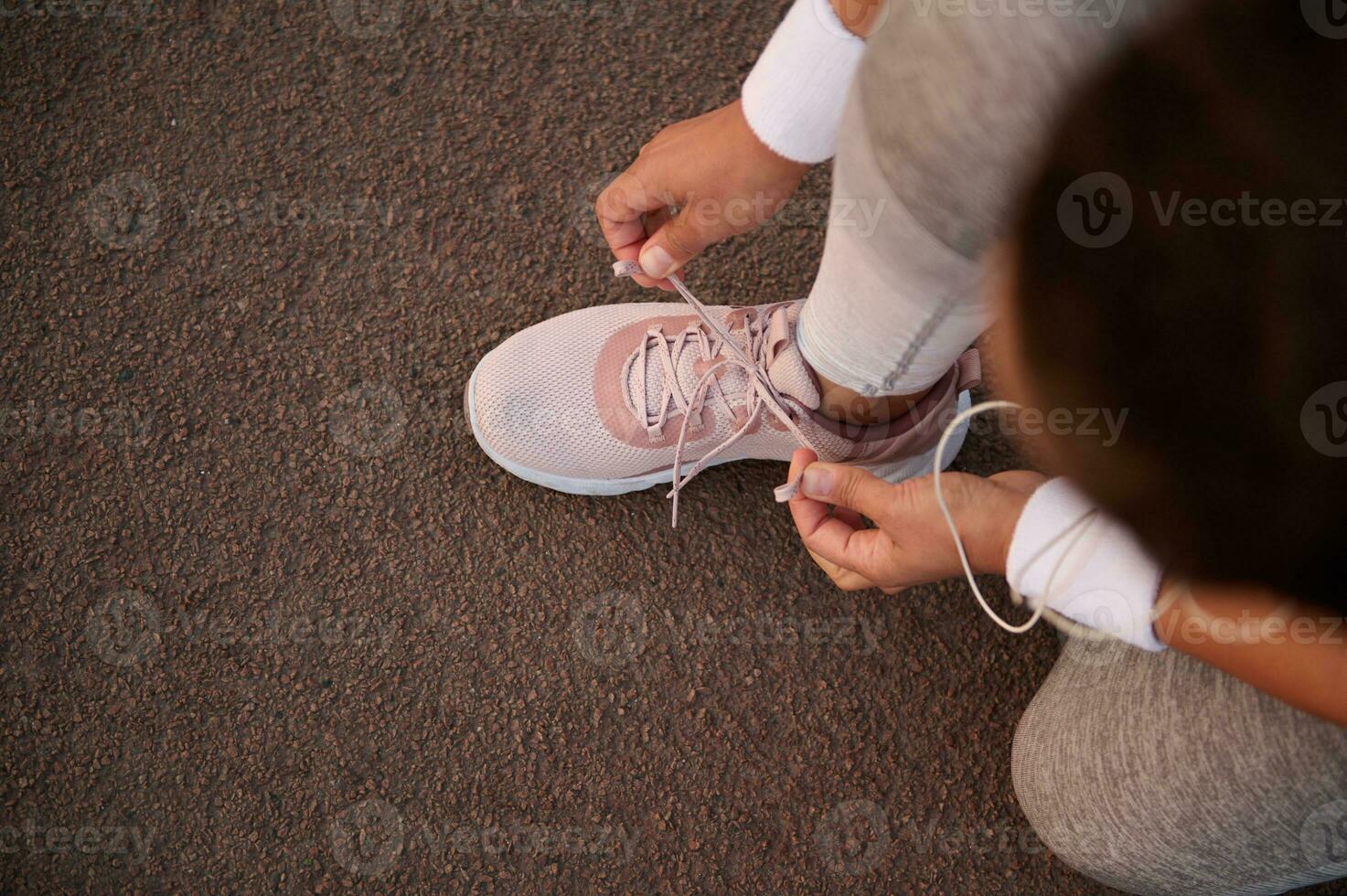 Haut vue de un athlète attacher baskets lacets accroupi sur une tapis roulant tandis que en train de préparer pour une courir Extérieur. sport, actif en bonne santé mode de vie, santé et corps se soucier concept avec copie espace photo