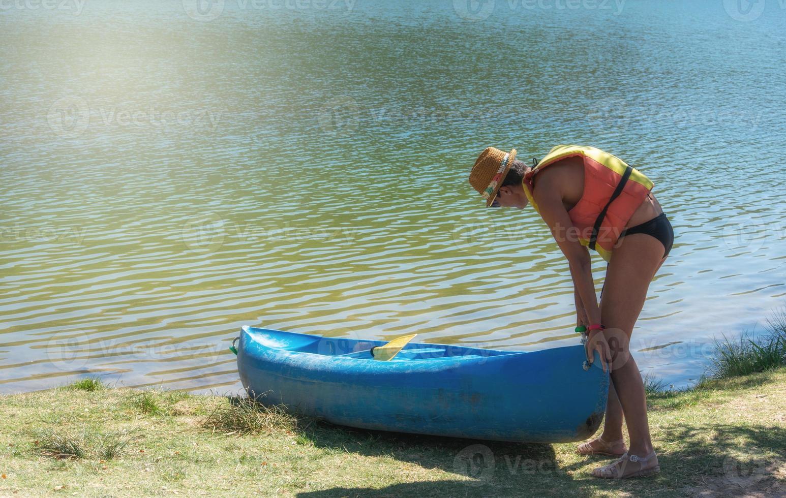 Femme en gilet de sauvetage poussant le canoë dans l'eau photo