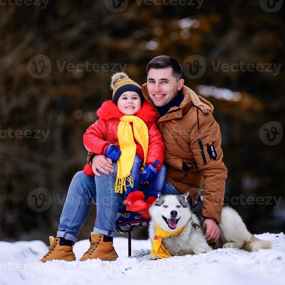 un père avec une fille chien husky se promène dans la forêt d'hiver. photo