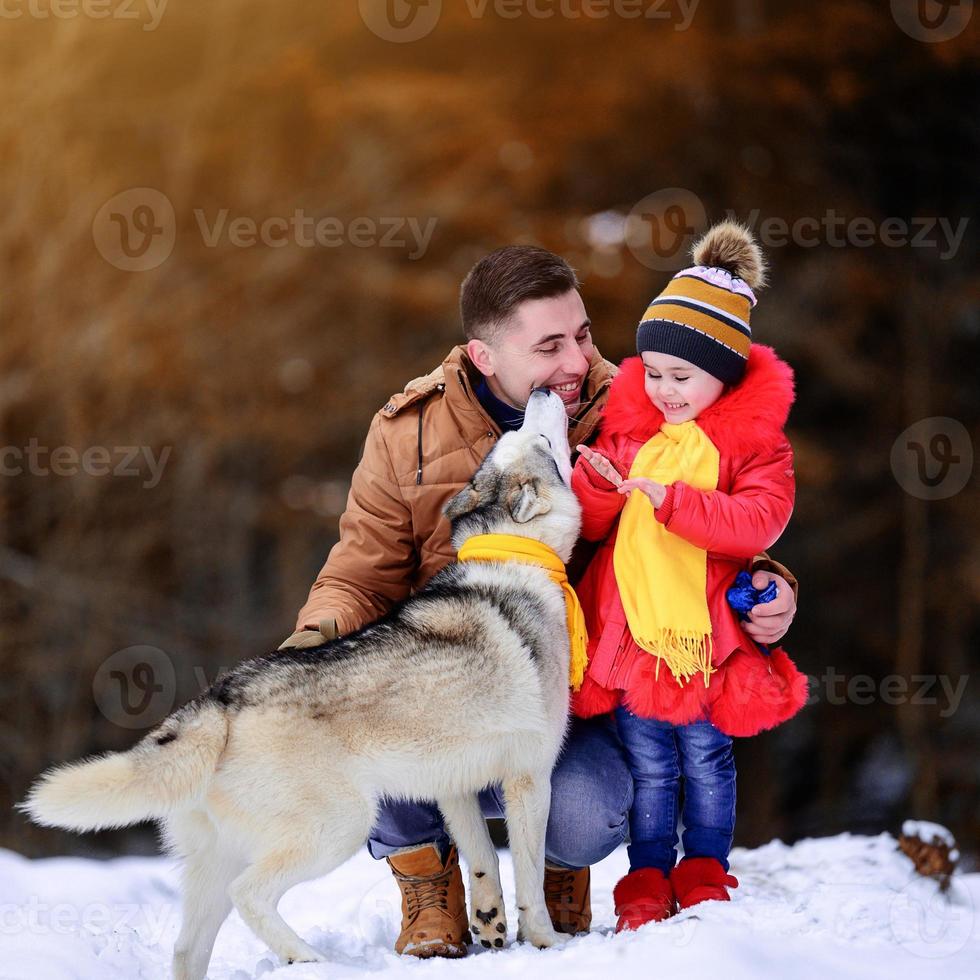 père avec fille et leur animal de compagnie dans le parc d'hiver, marchant avec un chien. photo